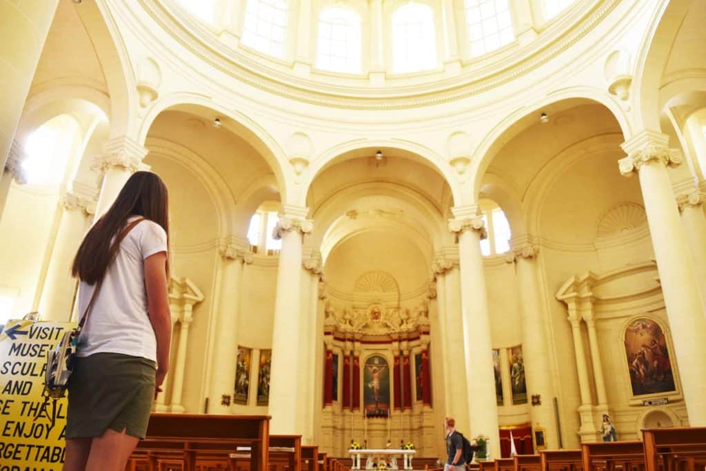 A woman standing and facing an altar.